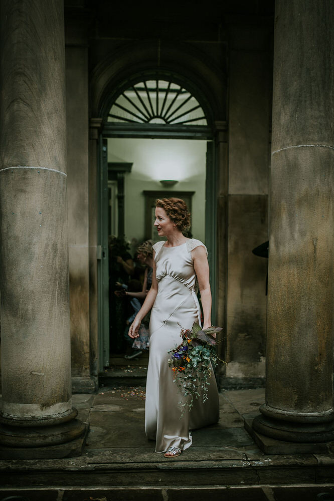 Bride with red hair in Gold Dress leaving her wedding ceremony holding bouquet of wild flowers